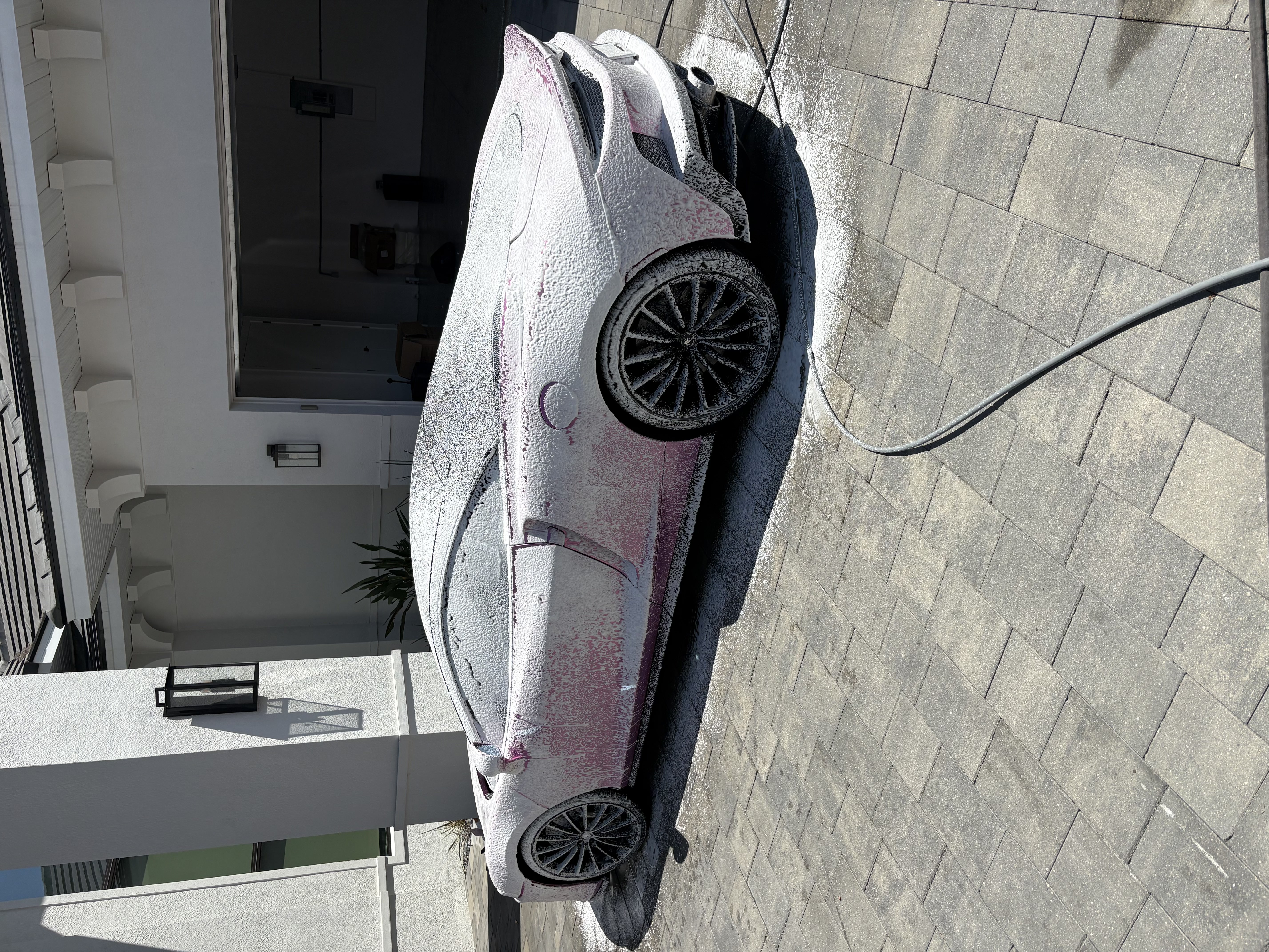 Pink McLaren GT covered in foam during a mobile hand wash